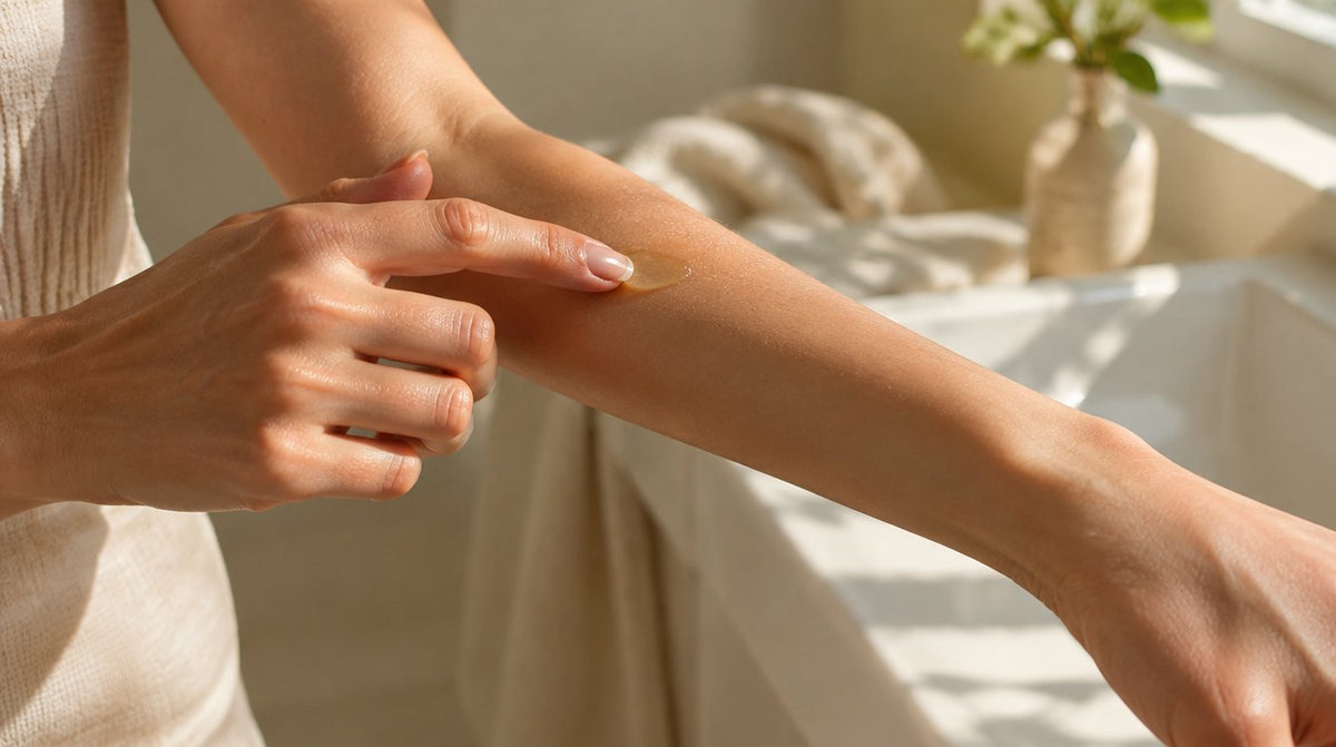 A fingertip with a small dab of clear tanning jelly about to be spread thinly along a forearm